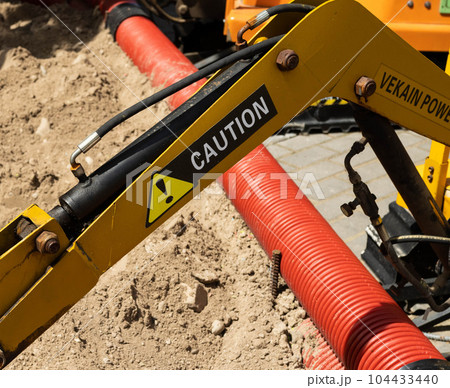 A yellow boom with a bucket near a children's mini excavator in an amusement park. Entertainment for children. 104433440