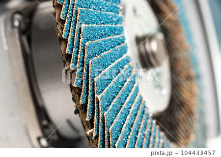 Professional angle grinder with flap wheel for processing wooden surfaces. Construction power tool. Industry, close-up Professional angle grinder with flap wheel for processing wooden surfaces. Construction power tool. Industry, close-up 104433457