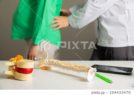 A neurologist doctor examines a pregnant woman who has back pain from muscle strain during pregnancy. Load on the spine A neurologist doctor examines a pregnant woman who has back pain from muscle strain during pregnancy. Load on the spine 104433470