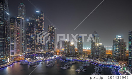 Panorama showing Dubai marina tallest skyscrapers and yachts in harbor aerial night timelapse. Panorama showing Dubai marina tallest skyscrapers and yachts in harbor aerial night timelapse. 104433942