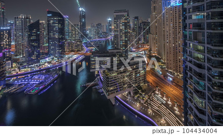 Aerial view to Dubai marina skyscrapers around canal with floating boats night timelapse Aerial view to Dubai marina skyscrapers around canal with floating boats night timelapse 104434004