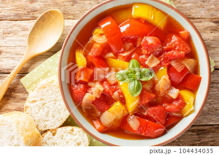 Delicious stewed colorful bell peppers with onions, garlic and tomatoes close-up in a bowl. Horizontal top view 104434035