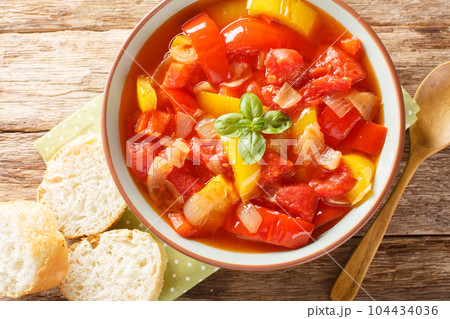 Warm salad of stewed colorful bell peppers with onions and tomatoes close-up in a bowl. Horizontal top view 104434036