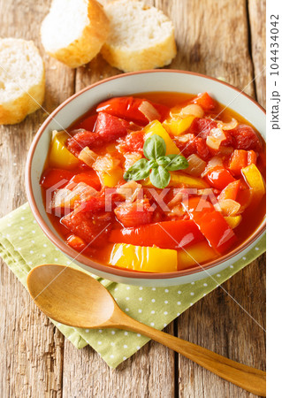 Vegetarian stew of colorful bell peppers with onions and tomatoes close-up in a bowl. Vertical 104434042