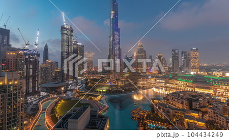 Skyscrapers rising above Dubai downtown day to night timelapse surrounded by modern buildings aerial top view Skyscrapers rising above Dubai downtown day to night timelapse surrounded by modern buildings aerial top view 104434249