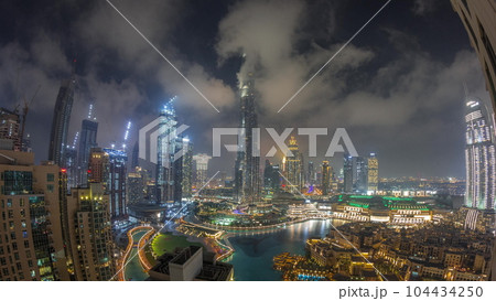 Skyscrapers rising above Dubai downtown night timelapse surrounded by modern buildings aerial top view 104434250