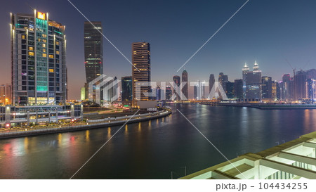 Modern city architecture in Business bay district. Panoramic view of Dubai's skyscrapers day to night timelapse Modern city architecture in Business bay district. Panoramic view of Dubai's skyscrapers day to night timelapse 104434255