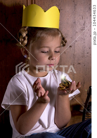 Cute little girl playing with a toy frog, pretending to be a princess 104434633