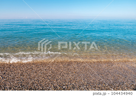 natural background shot of a pebbly beach with no people, no one. Scenic view of empty pebble sea coast on a sunny day 104434940