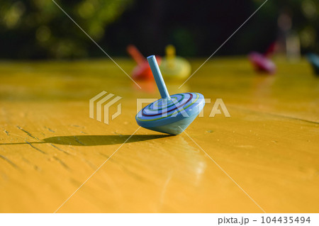 The blue spinning top still spinning on the table while other fell The blue spinning top still spinning on the table while other fell 104435494