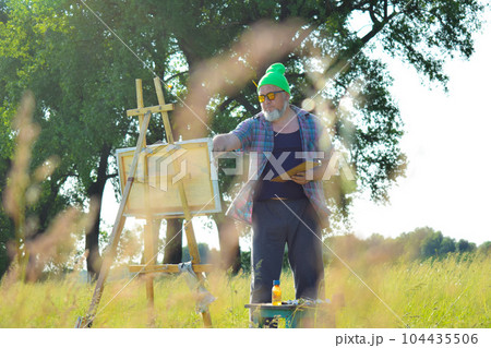 Working artisan at meadow in sunrise alongside meadow grass Working artisan at meadow in sunrise alongside meadow grass 104435506