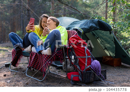 Mom and daughter during an online video call in a forest camp. 104435778