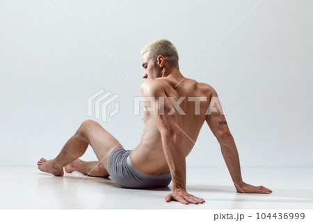 Young handsome man with muscular, relief, fit, strong body posing on floor in underwear against grey studio background Young handsome man with muscular, relief, fit, strong body posing on floor in underwear against grey studio background 104436999
