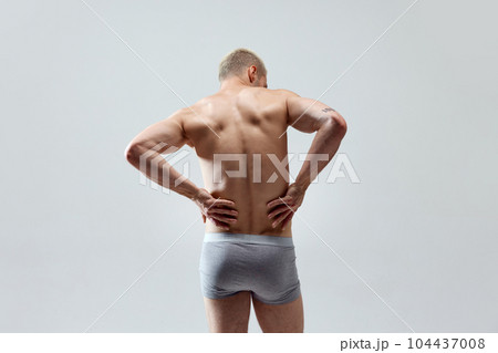 Rear view image of young man with muscular, relief, fit, strong healthy body, back, posing in underwear shirtless 104437008