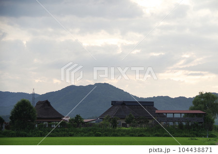 公共施設の茅葺き屋根と山の見える郊外の夕方の風景 公共施設の茅葺き屋根と山の見える郊外の夕方の風景 104438871