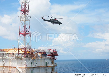 Helicopter Landing Officer communicating with pilot and copilot for service on ground and support as the pilot required. The helicopter landing on the deck in oil and gas platform 104438935