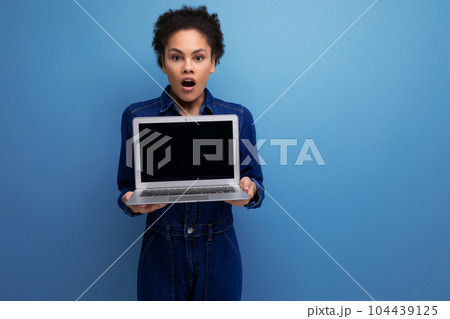 young successful woman with dark skin and black curly hair dressed in a blue denim suit demonstrates young successful woman with dark skin and black curly hair dressed in a blue denim suit demonstrates 104439125