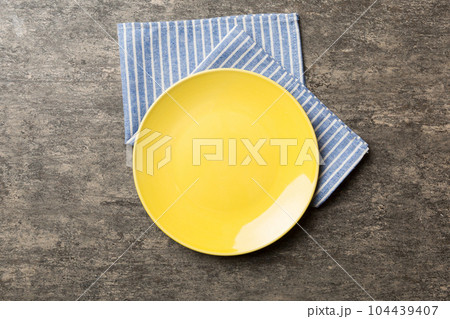 Top view on colored background empty round yellow plate on tablecloth for food. Empty dish on napkin with space for your design 104439407