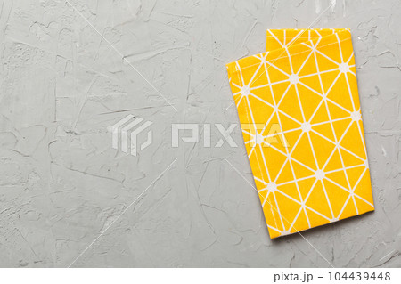 top view with yellow empty kitchen napkin isolated on table background. Folded cloth for mockup with copy space, Flat lay. Minimal style 104439448