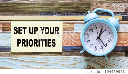 White notepad with text Set up your priorities , color background with alarm clock White notepad with text Set up your priorities , color background with alarm clock 104439948