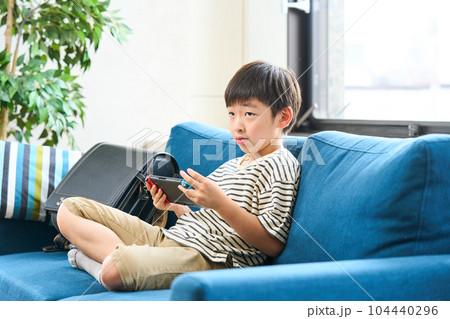 ソファーに座りゲームをする小学生 ソファーに座りゲームをする小学生 104440296