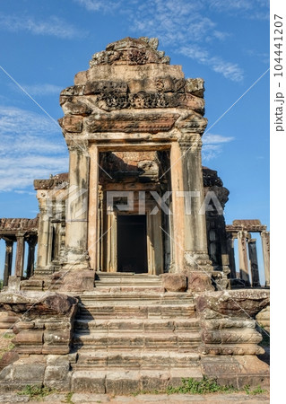 Photograph of an ancient stone structure in the famous deserted city of Angkor, Khmer, on a bright day. 104441207