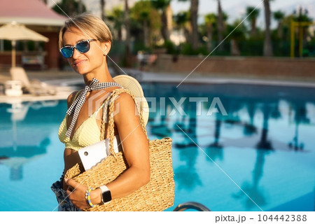 Young happy woman going to work with laptop in summer sunny day near the pool 104442388