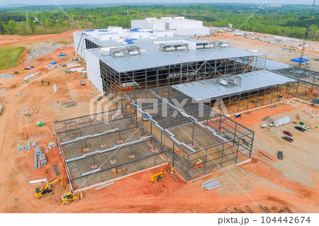 Steel truss frames are being constructed as part of construction an industrial warehouse building Steel truss frames are being constructed as part of construction an industrial warehouse building 104442674
