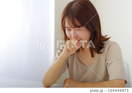 口に手をあてる辛そうな表情の女性 104444973