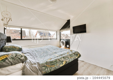 a bed in a room with a tv on the wall next to it and an air condition heater nearby 104445079