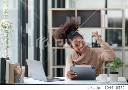 American African Woman working in the office with computer phone and Tablet. 104446522