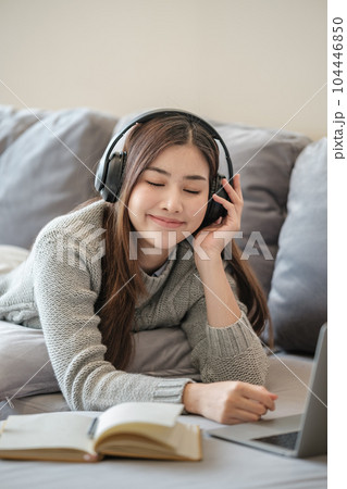 Beautiful asian woman write a book on sofa with laptop in living room. Beautiful asian woman write a book on sofa with laptop in living room. 104446850