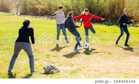 Cheerful teen friends playing with ball outdoors 104448144