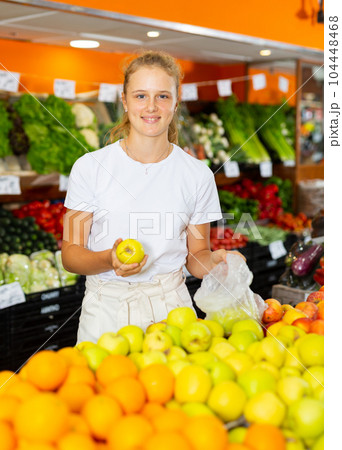 Young woman purchaser choosing apples in grocery 104448468