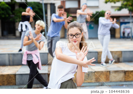 Teen girl dancing modern choreography with group outdoors 104448636