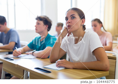 Teen girl listening to lecturer and writing in notebook Teen girl listening to lecturer and writing in notebook 104448775