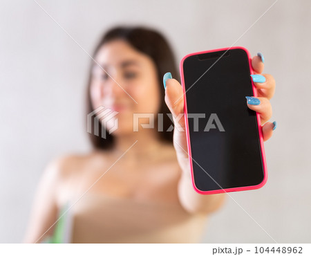 Young smiling woman posing with phone in studio 104448962