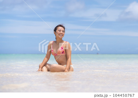 遠浅のビーチで微笑むビキニ姿の若い女性 104450767