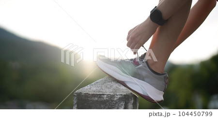 Running shoes. close up female athlete tying laces for jogging on road. Runner ties getting ready for training. Sport lifestyle. copy space 104450799