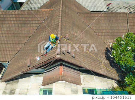 Worker man repairing eaves and tile of the old roof.. Worker man repairing eaves and tile of the old roof.. 104451615