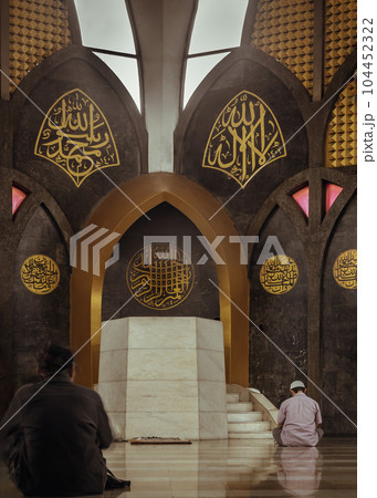 Religious muslim men sits and recite prayers for God on the floor in the Central Mosque and Islamic Center of Thailand. Religious muslim men sits and recite prayers for God on the floor in the Central Mosque and Islamic Center of Thailand. 104452322