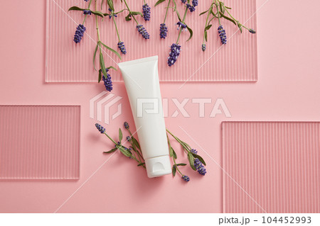 Abstract minimalist scene for advertising and branding product with lavender ingredient. On the pink background, a white plastic tube decorated with fresh lavender flower and acrylic sheet. Abstract minimalist scene for advertising and branding product with lavender ingredient. On the pink background, a white plastic tube decorated with fresh lavender flower and acrylic sheet. 104452993
