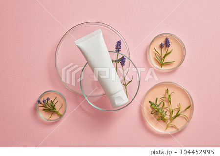 Against the pink background, an empty plastic bottle decorated with some petri dishes containing fresh lavender and essence. Mockup with blank space for design, advertising and branding product Against the pink background, an empty plastic bottle decorated with some petri dishes containing fresh lavender and essence. Mockup with blank space for design, advertising and branding product 104452995