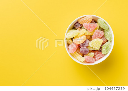 Mix of fruity jelly candy in bowl on yellow background. Top view. Mix of fruity jelly candy in bowl on yellow background. Top view. 104457259