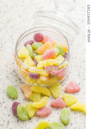 Mix of fruity jelly candy in jar on kitchen table. 104457265