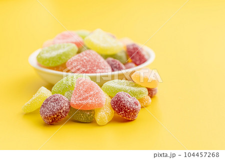 Mix of fruity jelly candy in bowl on yellow background. 104457268