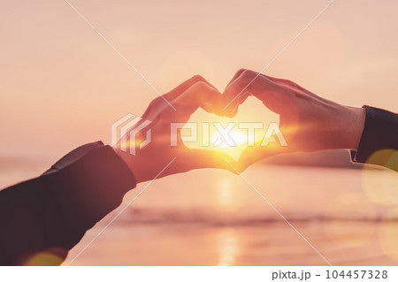 Female hands heart shape on nature bokeh sun light wave and blur tropical sunset beach abstract background. Copy space of happy love travel and freedom in nature concept. Vintage tone color style. Female hands heart shape on nature bokeh sun light wave and blur tropical sunset beach abstract background. Copy space of happy love travel and freedom in nature concept. Vintage tone color style. 104457328