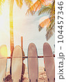 Surfboard and palm tree with blue sky on beach background. Travel adventure sport and summer vacation concept. Vintage tone filter effect color style. 104457346