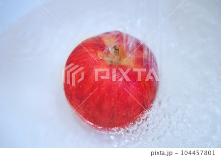 水で洗われるリンゴ 104457801