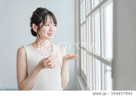 薬・サプリメント・ビタミン剤・整腸剤を飲む若いアジア人女性 薬・サプリメント・ビタミン剤・整腸剤を飲む若いアジア人女性 104457942